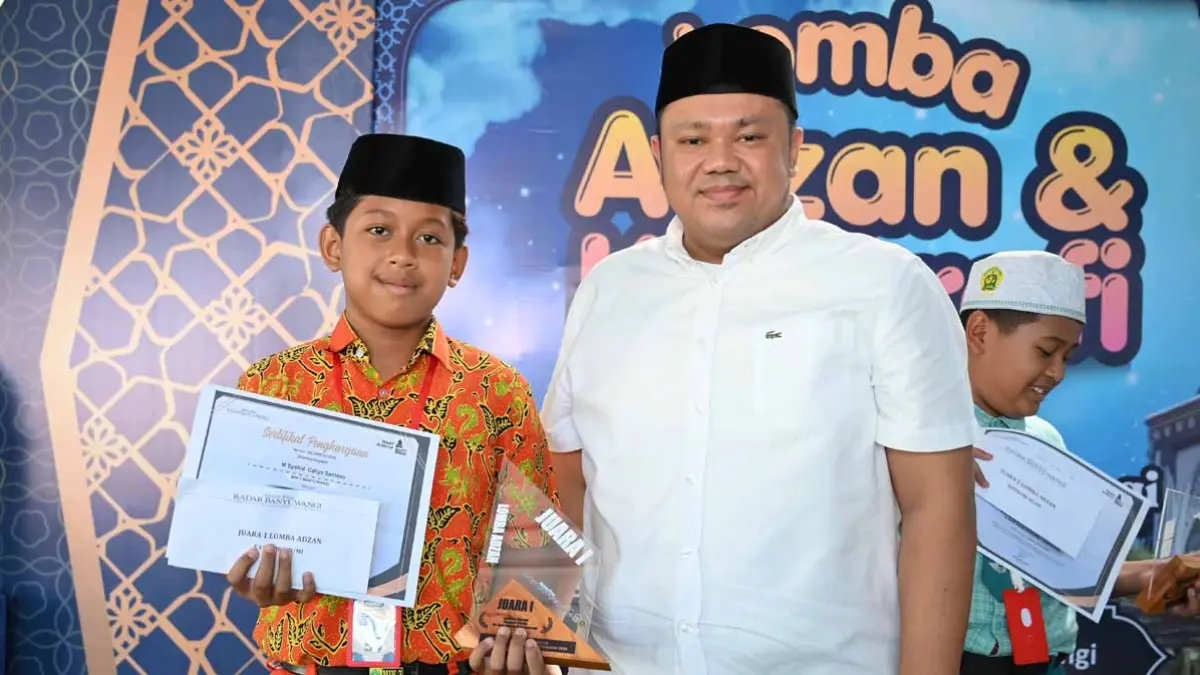 Founder Masjid Al-Ma’ruf Ferdy Elfian menyerahkan piala kepada juara 1 lomba azan M Syahid Cahyo Santoso dari MIN 3 Banyuwangi. (Ramada Kusuma/Radar Banyuwangi)