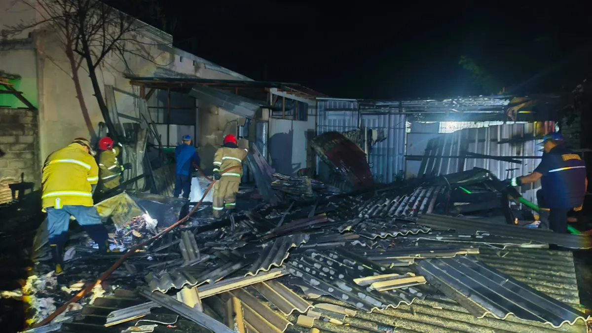 Petugas Damkarmat berusaha memadamkan kobaran api yang melumat warung kopi asem milik Ita Wahyuni di Jalan Trunojoyo, Kebalenan, Jumat dini hari (19/6). (Damkarmat Banyuwangi)
