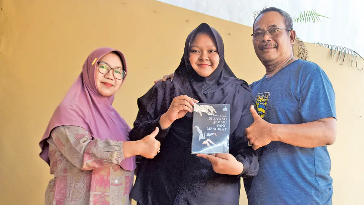 Wahyu Triana Risnanti Putri didampingi Srianah Putri dan Haris Nusantoro menunjukkan buku antologi puisi karyanya di kediamannya di Desa Tembokrejo, Kecamatan Muncar. (Zamrozi Wahyu/Radar Banyuwangi)
