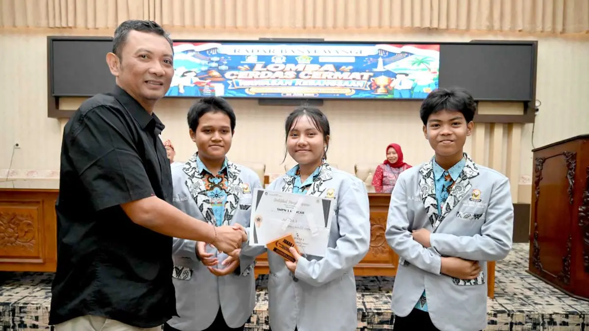 BERI APRESIASI: Ketua DPRD Banyuwangi menyerahkan piala kepada juara 1 LCC dari   tim SMPN 1 Muncar. (Ramada Kusuma/Radar Banyuwangi)