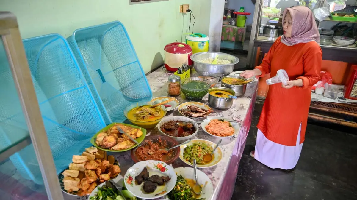 PRASMANAN: Sugiarti menyajikan aneka menu di Warung Pondok Nurani yang terletak di gang kecil Jalan Agus Salim, Banyuwangi, Jumat (26/6). (Ramada Kusuma/Radar Banyuwangi)