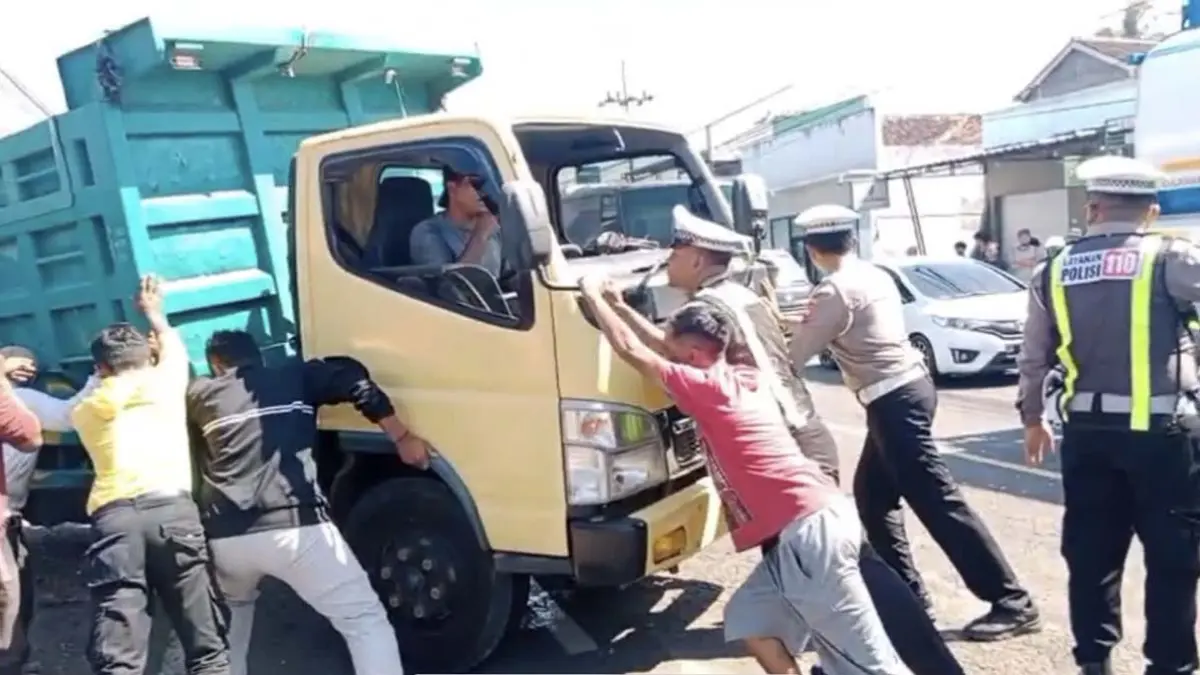 GOTONG ROYONG: Polisi dan warga mendorong truk yang terlibat kecelakaan di jalan raya Desa Dadapan, Kecamatan Kabat, Sabtu (27/6). (Satlantas Polresta Banyuwangi)