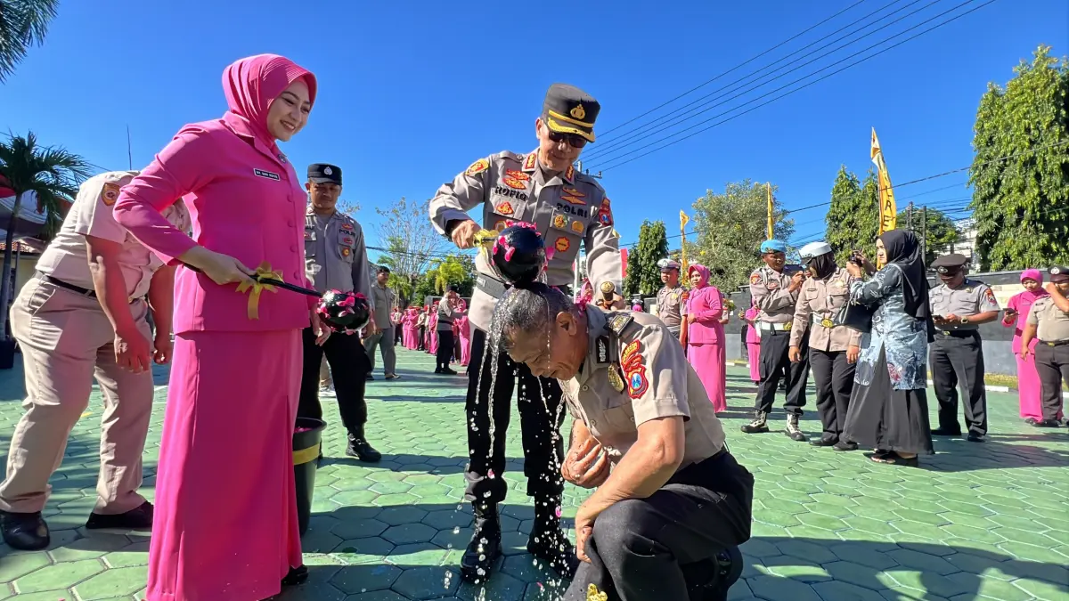 MOMEN KENAIKAN PANGKAT: Kapolresta Banyuwangi Kombespol  Rofiq Ripto Himawan menyiramkan air kembang kepada anggotanya yang naik pangkat, Selasa (30/6). (HUMAS POLRESTA FOR RABA)