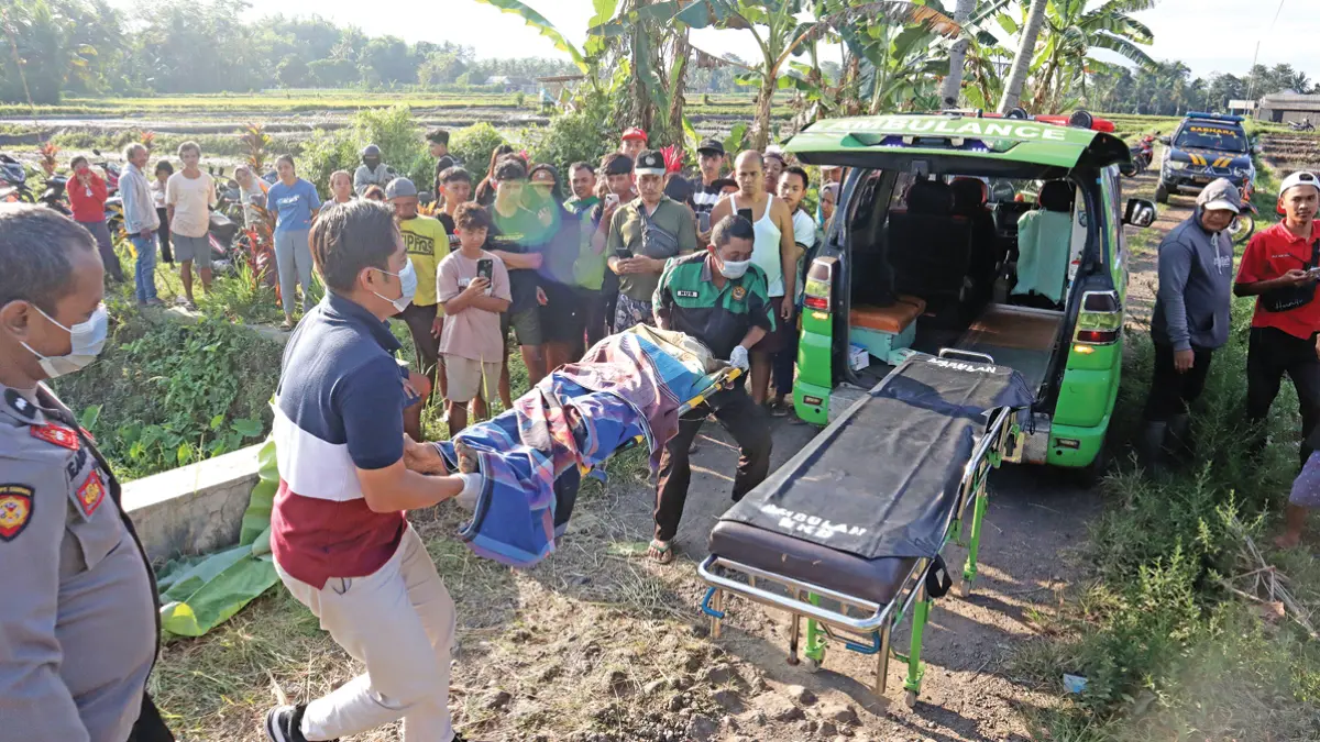 BIKIN GEMPAR: Polisi mengevakuasi jenazah pria yang ditemukan di persawahan Dusun Simbar, Desa Karangsari, Kecamatan Sempu, Rabu (1/7). (Salis Ali/Radar Banyuwangi)