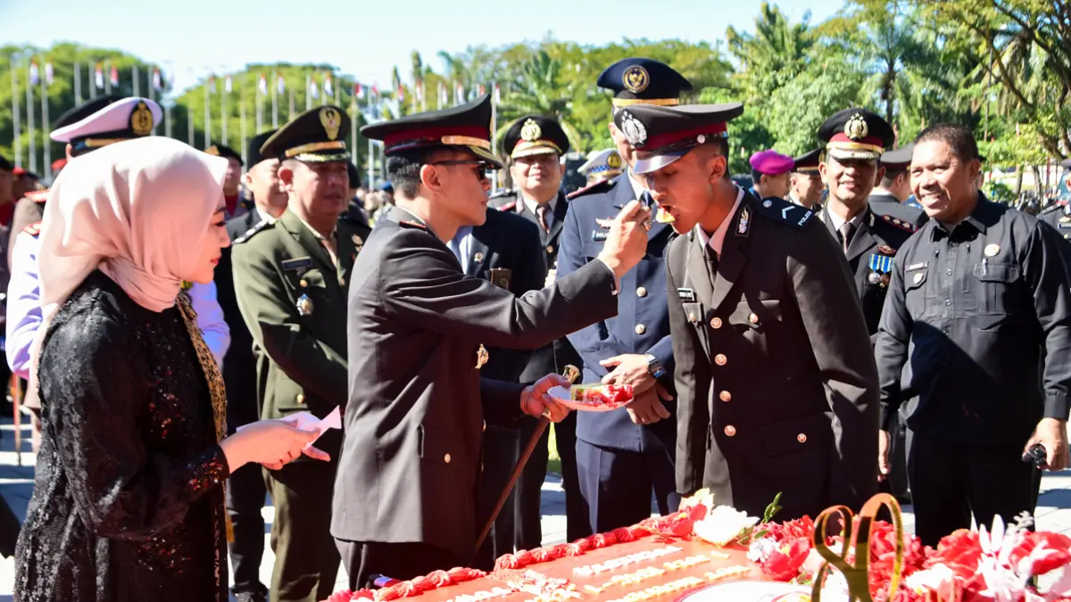 Kapolresta Banyuwangi Kombespol Dr Rofiq Ripto Himawan, SIK, SH, MH menyuapkan potongan kue tart kepada anggota termuda di Taman Blambangan, Kamis (1/7). (Ramada Kusuma/Radar Banyuwangi)