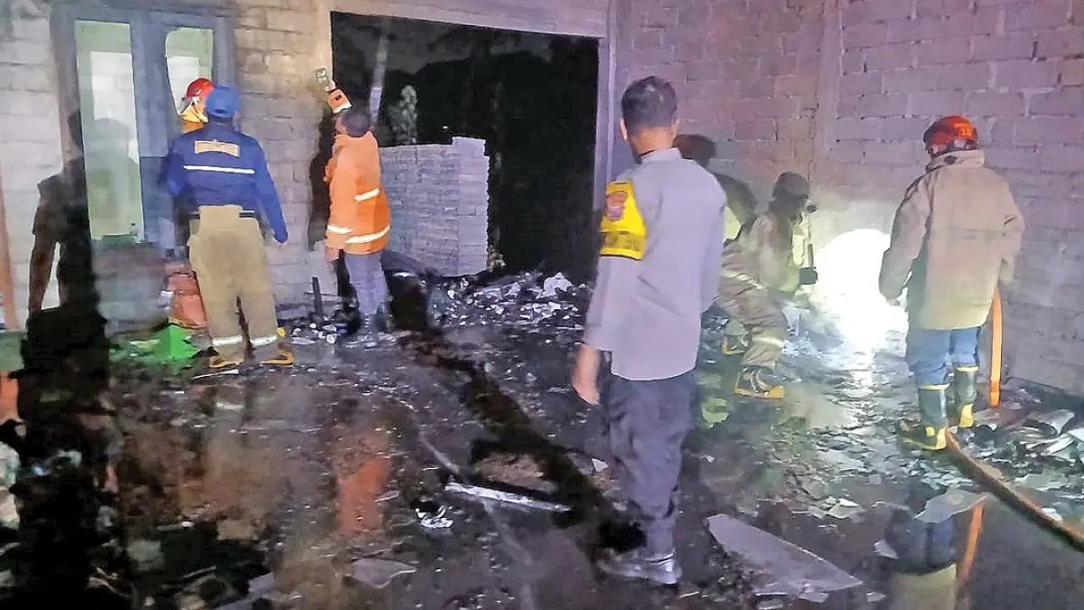 Anggota Polsek Cluring bersama tim Damkarmat membantu memadamkan api yang membakar garasi di depan rumah warga Desa Tamanagung, Kecamatan Cluring, pada Rabu malam (8/7). (Putu Ardana for Radar Banyuwangi)