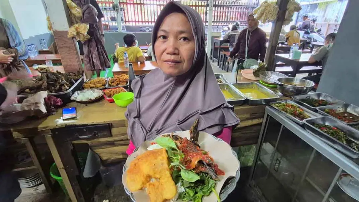 MENU ANDALAN: Musarofah menunjukkan menu pecek lele yang biasa dipesan pelanggan di Warung Sirot yang beralamat di Jalan Diponegoro nomor 245, Dusun Lidah, Kecamatan Gambiran. (Salis Ali/Radar Banyuwangi)