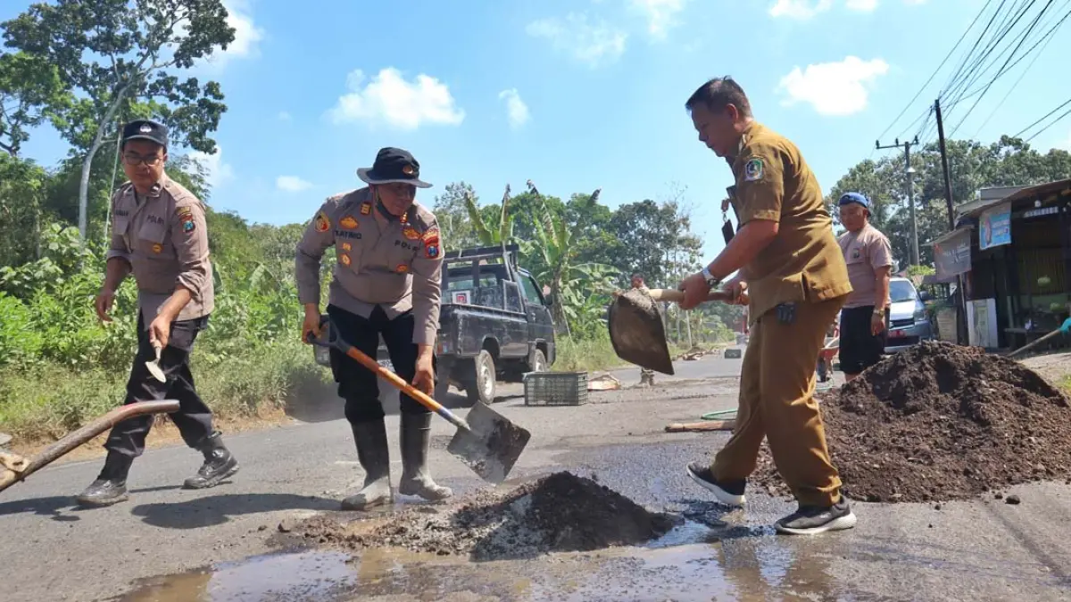 Camat Sempu Mujito dan Kapolsek AKP Satrio turun ke lapangan menambal jalan berlubang di sebelah timur kantor Kecamatan Sempu, Senin (13/7). (Salis Ali/Radar Banyuwangi)