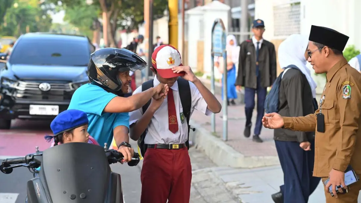 Kepala SMPN 1 Banyuwangi Ali Mustofa menyambut kedatangan siswa baru di pintu gerbang sekolah, Senin (13/7). (Ramada Kusuma/Radar Banyuwangi)