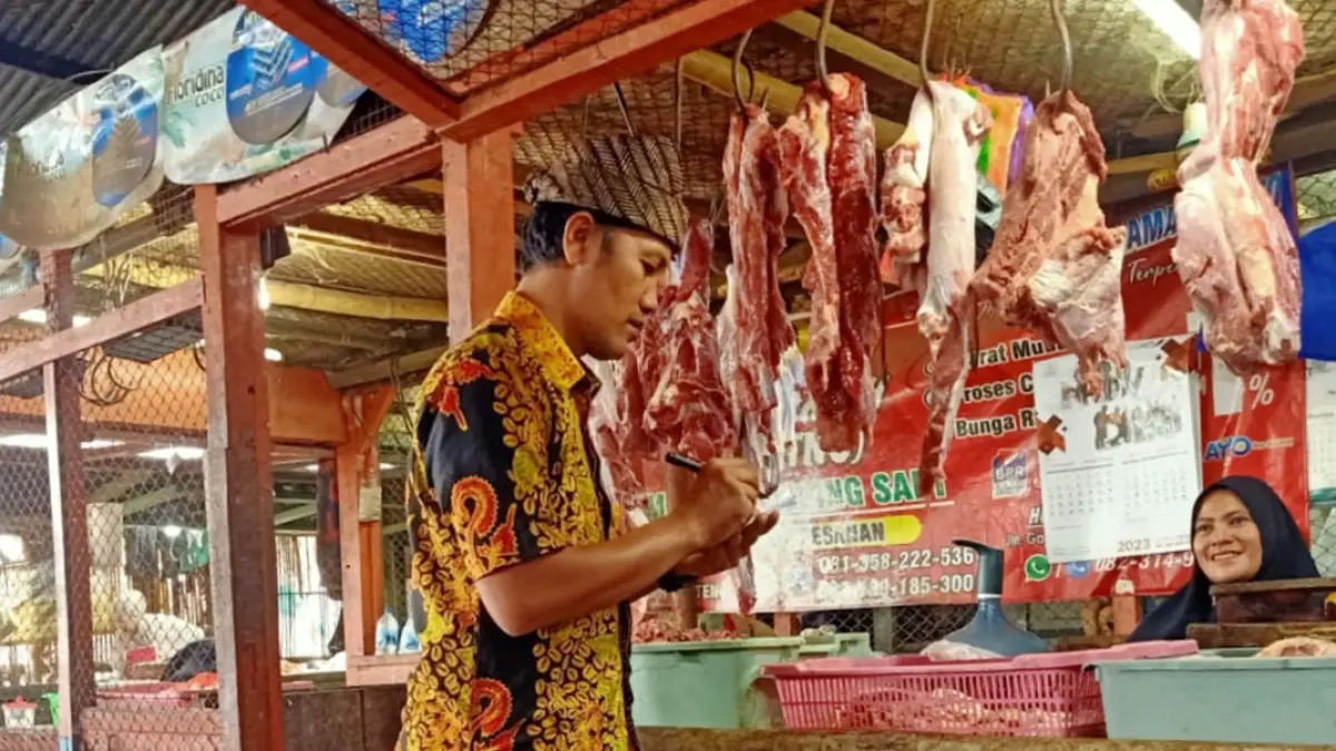 PEMANTAUAN HARGA: Arif Kurniawan mencatat harga komoditas yang dijual pedagang di Pasar Genteng I, Selasa (14/7). ARIF for Radar Banyuwangi)
