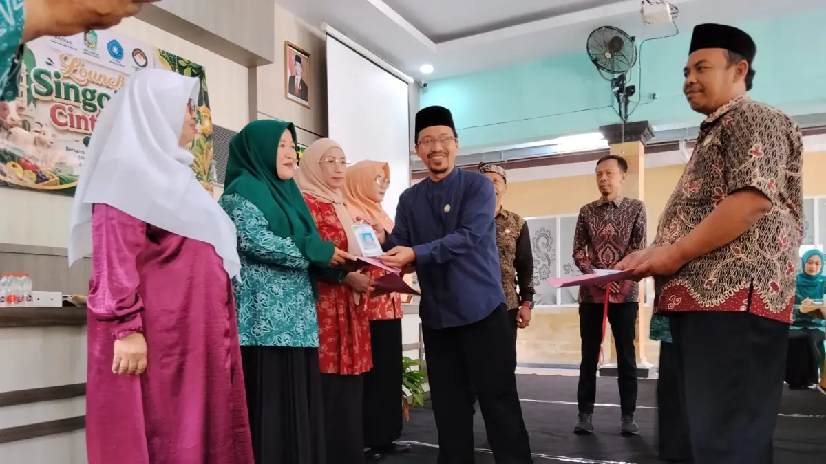 Komisioner Baznas Kabupaten Banyuwangi Lukman Hadi menyerahkan ID Card Si-Cat kepada ibu-ibu Tim Penggerak PKK Kecamatan Singojuruh di Kantor Desa Singojuruh pada Kamis pagi (16/7/2026). (Baznas Banyuwangi)