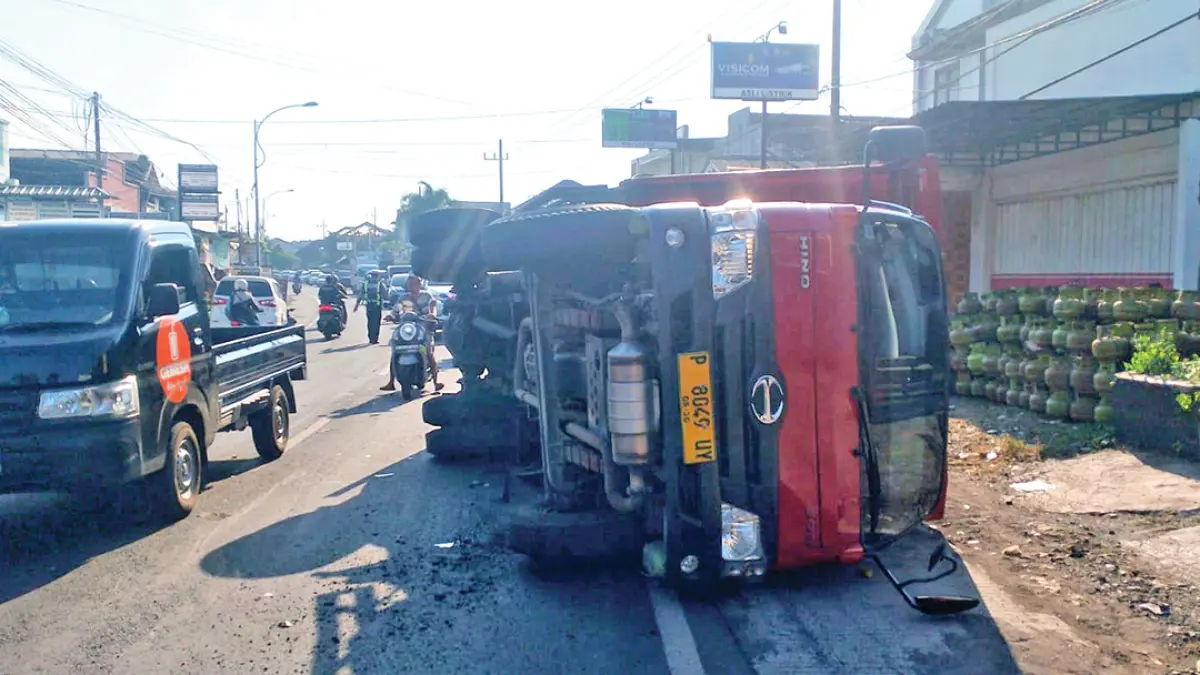 PICU KEMACETAN: Kondisi truk bermuatan tabung gas elpiji terguling di Jalan Raya Hasanudin, Dusun Krajan, Desa Gentengwetan, Kecamatan Genteng, Kamis sore (16/7). (Irwanto for Radar Banyuwangi)