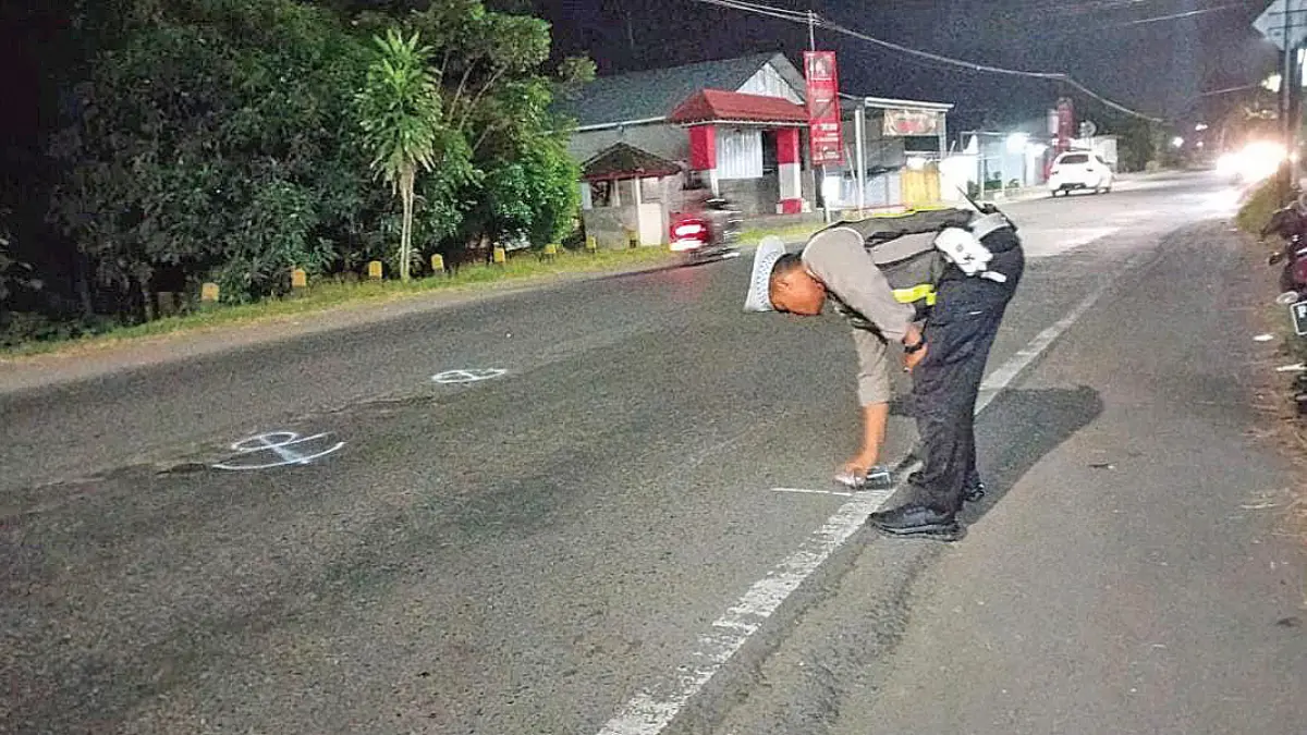 PAKAI CAT SEMPROT: Anggota Satlantas Polresta Banyuwangi menandai lokasi kecelakaan di Jalan Raya Desa Mangir, Kecamatan Rogojampi, pada Minggu (19/7). (Pepri for Radar Banyuwangi)