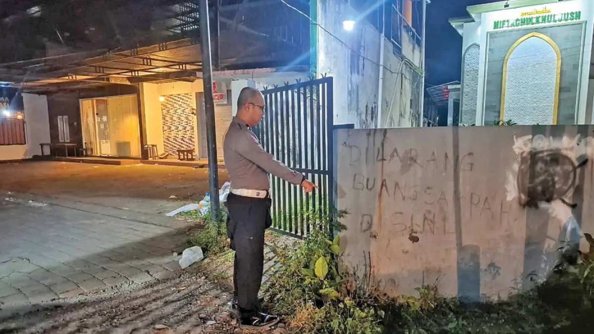 TKP: Anggota Polsek Genteng menunjukkan tembok yang ditabrak pengendara motor di Jalan Samiran, Desa Setail, Kecamatan Genteng, pada Minggu malam (19/7). (Foto: Polsek Genteng)