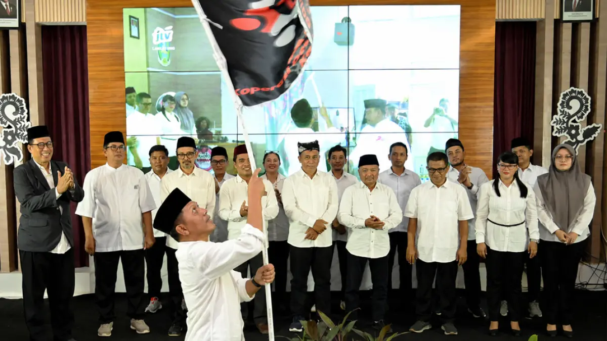 Ketua Asosiasi KDKMP Banyuwangi Imam Maskun mengibarkan bendera koperasi usai mengukuhkan pengurus Asosiasi KDKMP di aula Kantor Dispendik Banyuwangi, Rabu (22/7). (Ramada Kusuma/Radar Banyuwangi)