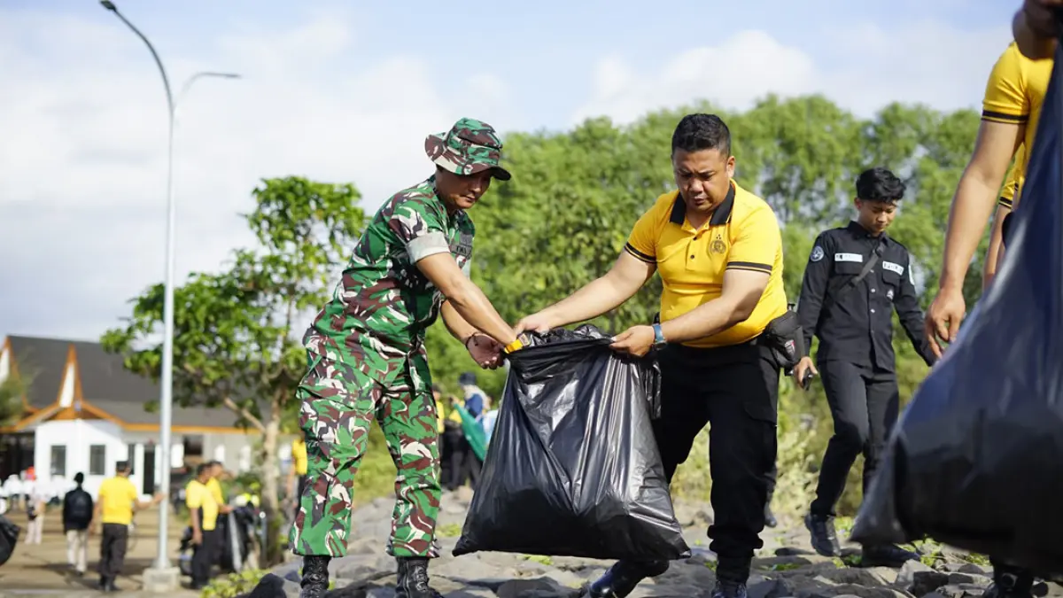 Personel Polresta Banyuwangi bersama TNI turut memebrihkan sampah di pantai sekitar Kampung Nelayan Merah Putih (KNMP), Kelurahan Lateng, Banyuwangi, Selasa (21/7). (Humas Polresta Banyuwangi)