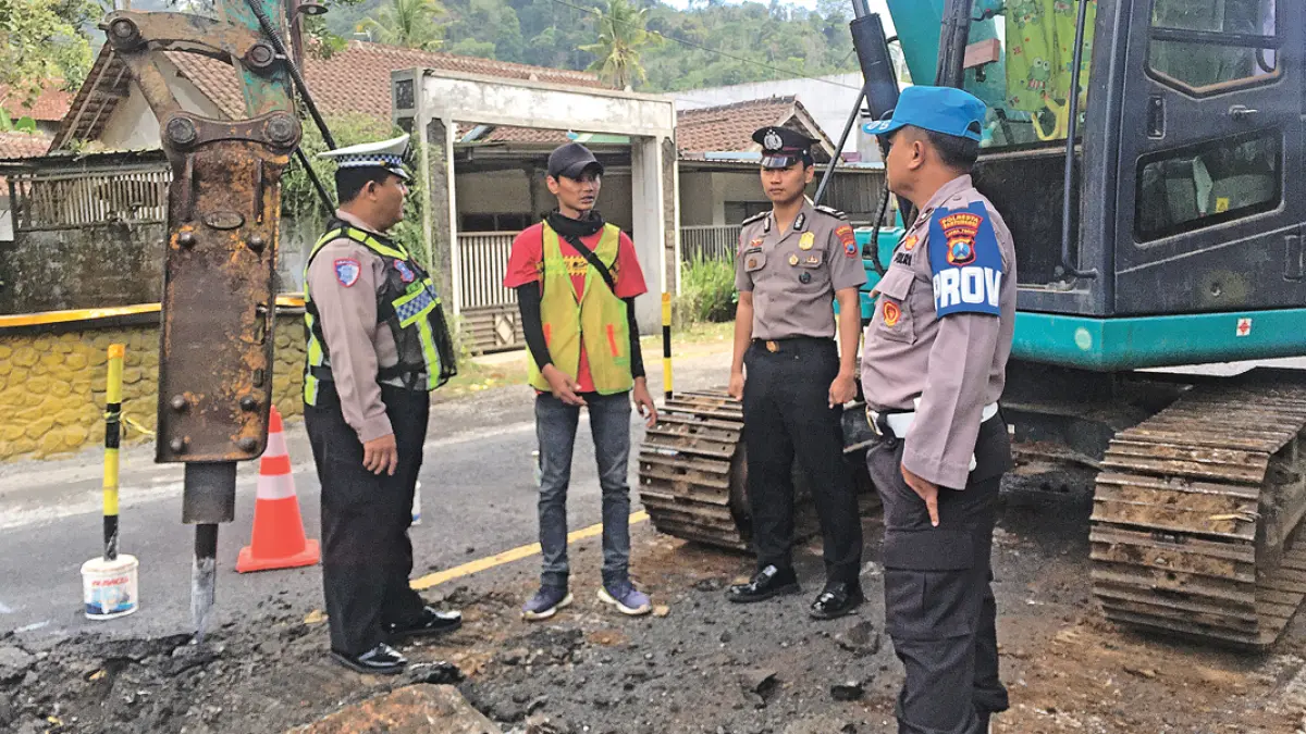 Pihak kepolisian memantau pekerjaan perbaikan jembatan Kajarharjo (KM SBY 247 +057) di Desa Kajarharjo, Kecamatan Glenmore, Kamis (23/7). (Salis Ali/Radar Banyuwangi)