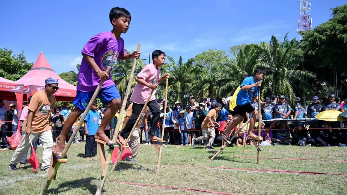 Anak-anak bermain egrang dalam Festival Memengan Tradisional di Taman Blambangan. Siapa yang cepat di garis finis, merekalah pemenangnya. (Ramada Kusuma/Radar Banyuwangi)