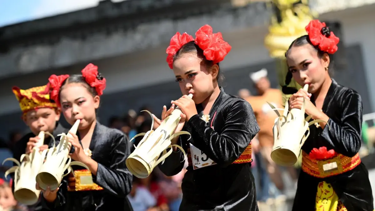 TEROMPET TRADISIONAL: Anak-anak meniup terompet yang bahannya dari janur dalam Festival Memengan Tradisional. (Ramada Kusuma/Radar Banyuwangi)