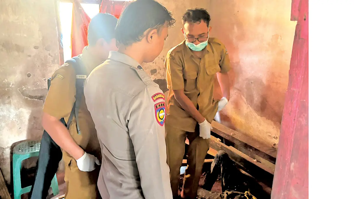 OLAH TKP: Anggota Polsek Gambiran bersama tim medis melakukan pemeriksaan jasad ODGJ yang ditemukan meninggal dunia di rumahnya, Desa Purwodadi, Kecamatan Gambiran, Senin (27/7). (Dwi Wijayanto for Radar Banyuwangi)