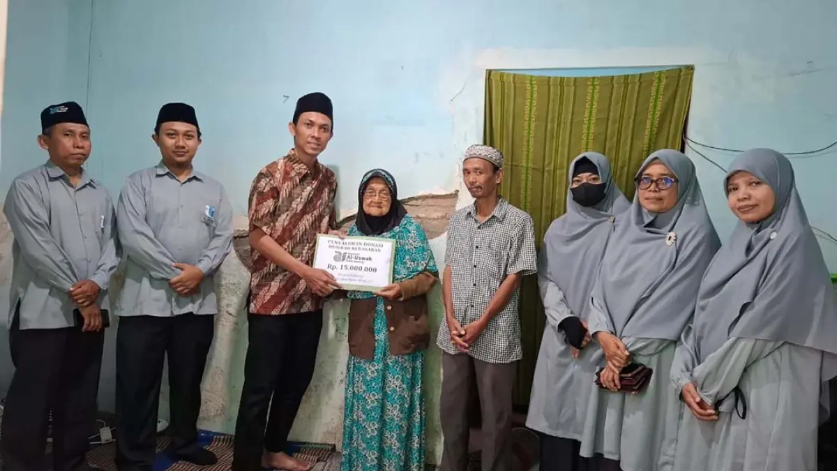 PEDULI SESAMA: Direktur Pendidikan Yayasan Al Uswah Banyuwangi Mochamad Amdani menyerahkan bantuan uang tunai kepada Suratin yang rumahnya terbakar pada Kamis (23/7) lalu. (Foto: Humas Al Uswah)