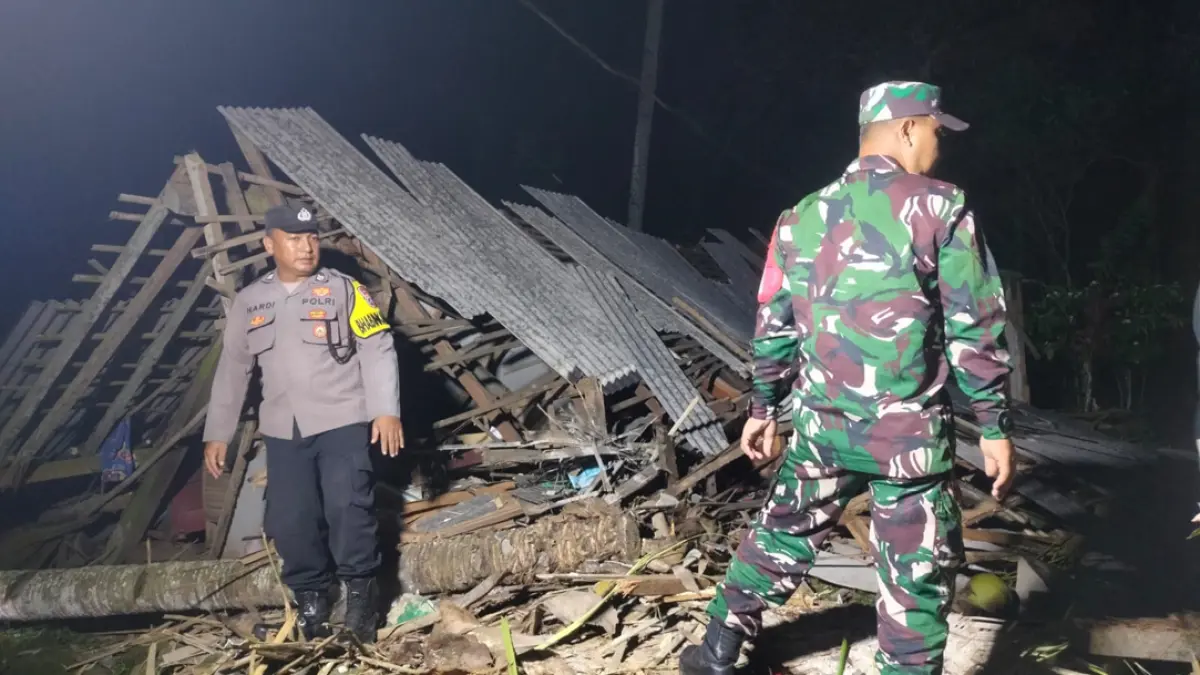 Personel Bhabinkamtibmas dan Babinsa mendatangi rumah warga Gombengsari yang roboh tertimpa pohon kelapa, Senin malam (26/7). (Madjid for Radar Banyuwangi)