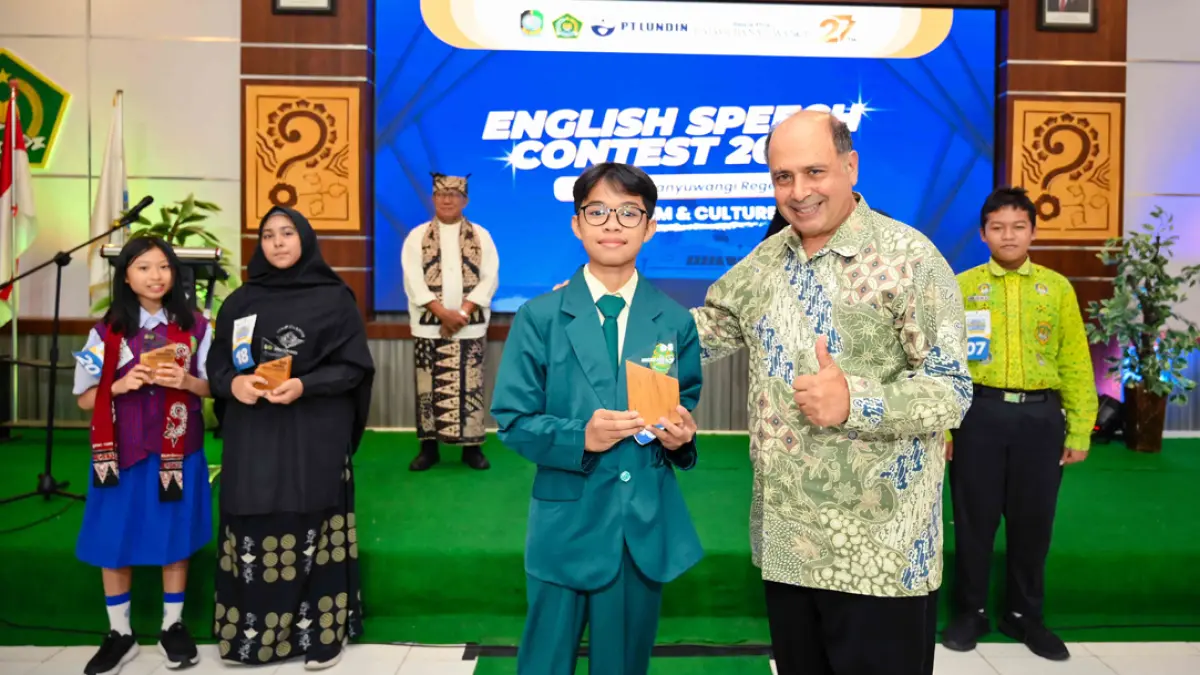 Siswa MTsN 3 Banyuwangi Ilman Rasyid Abdillah menerima piala dari Chris Tirris, guru asal Australia, sekaligus juri contest. (Ramada Kusuma/Radar Banyuwangi)