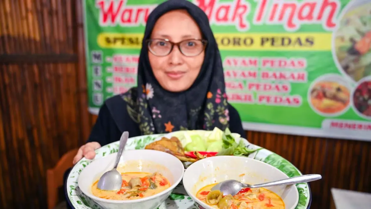 Evayanti menunjukkan lodeh koro pedas yang siap disantap. Resep koro pedas diturunkan dari nenaknya, Mak Tinah. Ramada Kusuma/Radar Banyuwangi)