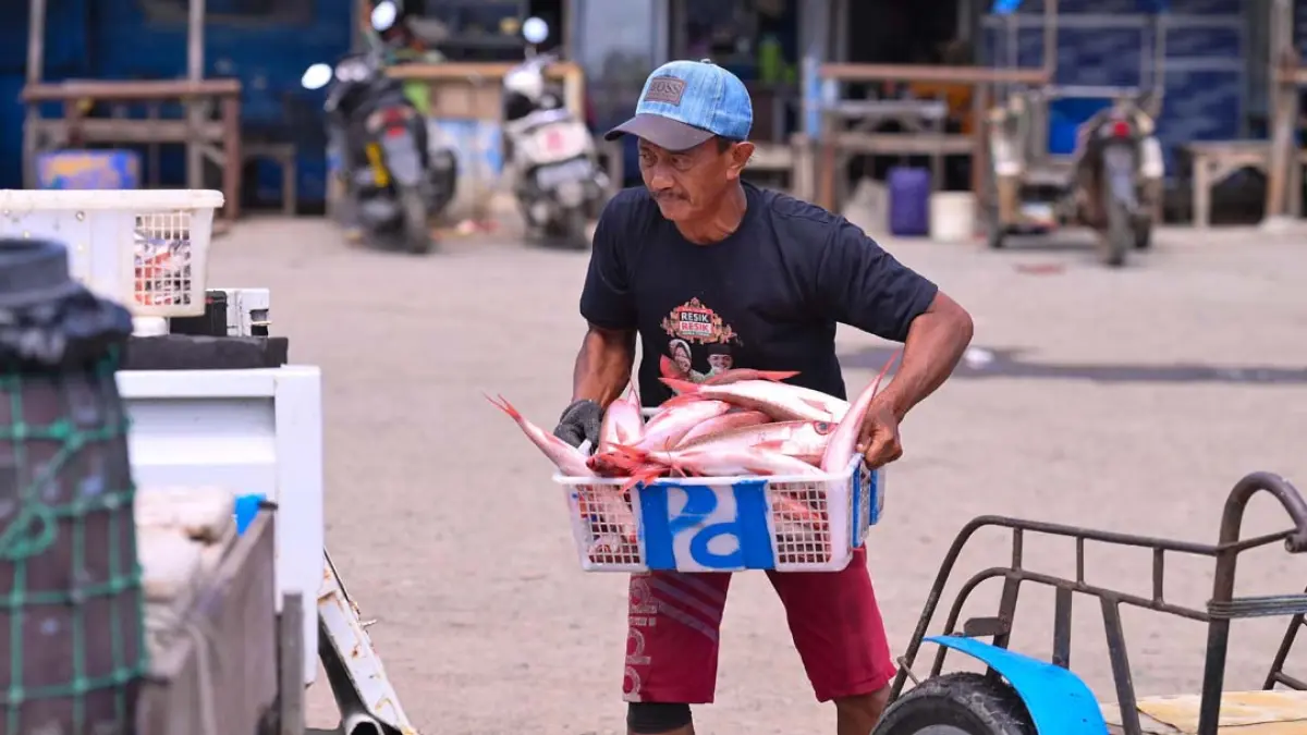 HASIL TANGKAPAN: Seorang juragan kapal memindah ikan ekor merah dari perahu ke tempat penampungan khusus di Pelabuhan Muncar, Sabtu (1/8). (Ramada Kusuma/Radar Banyuwangi)