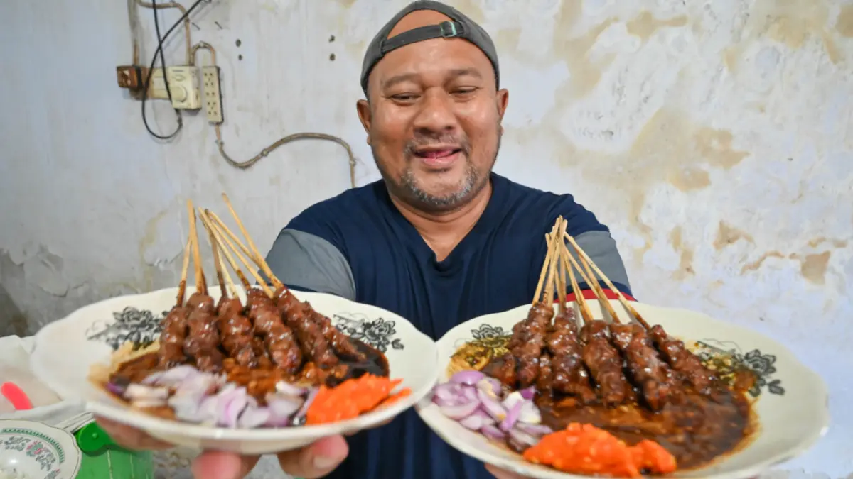 Bung Darmo menunjukkan hidangan sate kambing yang siap disantap di warungnya yang terletak di sebelah utara Indomaret Pakis Jalan S Parman Banyuwangi. (Ramada Kusuma/Radar Banyuwangi)