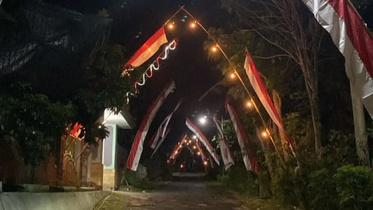 Menjelang HUT RI ke-81, warga menghias jalan lingkungan dengan bendera Merah Putih dan lampu warna-warni. (Anita untuk Radar Banyuwangi)