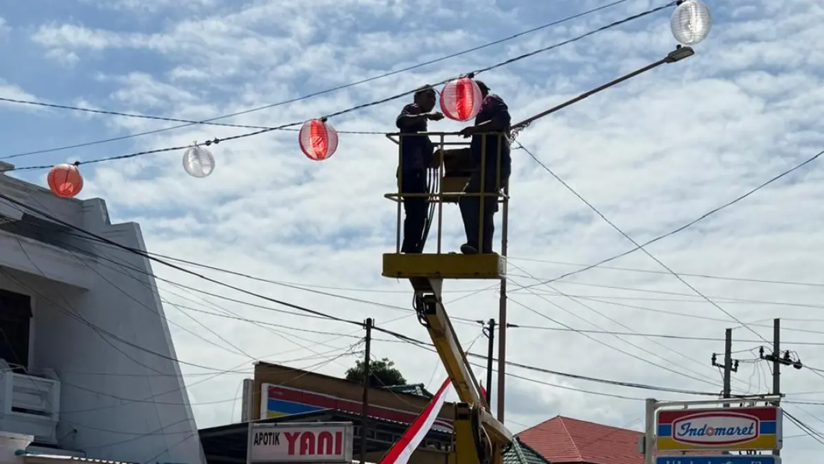 NAIK CRANE: Petugas dari PUCKPP Banyuwangi memasang lampion merah putih di sepanjang Jalan Ahmad Yani Banyuwangi, Selasa (11/8). (Syaifuddin/Radar Banyuwangi)