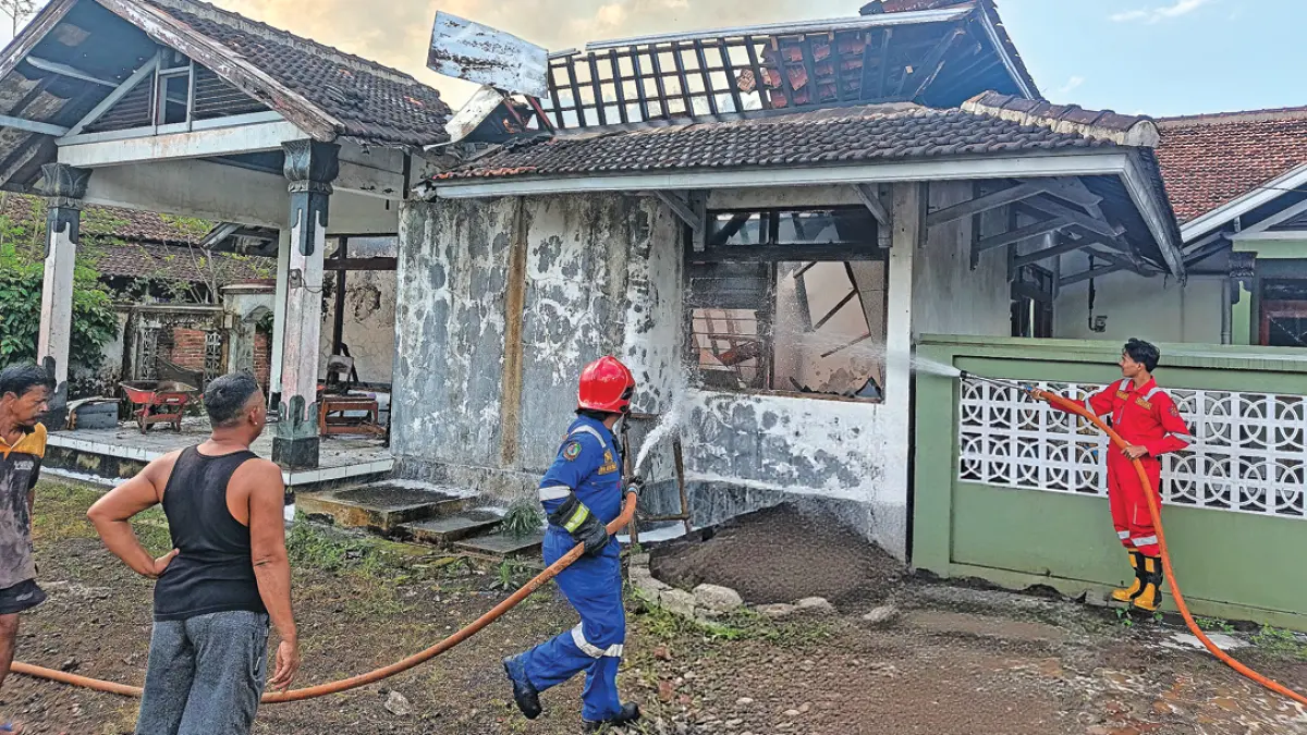 Petugas memadamkan api yang membakar dua rumah di Dusun Krajan 2, Desa Tampo, Kecamatan Cluring, Selasa (11/8). (Zamrozi Wahyu/Radar Banyuwangi)