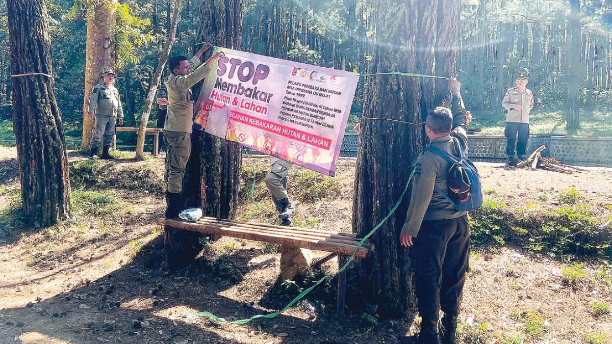 ANTISIPASI: Petugas gabungan memasang spanduk antisipasi karhutla di wilayah hutan Desa Bayu, Kecamatan Songgon, Kamis (13/8). (Salis Ali/Radar Banyuwangi)