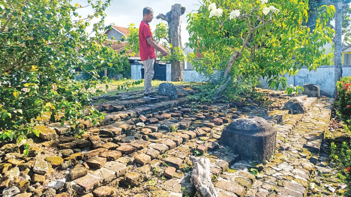 Santoso menunjukkan batu bata di area situs Umpak Songo di Desa Tembokrejo, Kecamatan Muncar, Kamis (13/8). (Zamrozi Wahyu/Radar Banyuwangi)
