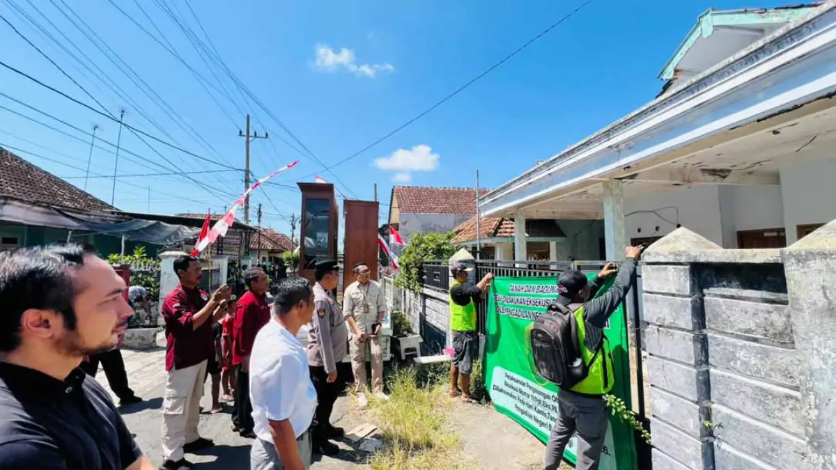 Tim eksekutor dari PN Banyuwangi dan kuasa hukum pemenang lelang Eko Sutrisno memasang banner bertuliskan tanah dan bangunan telah dilakukan eksekusi di Desa Gladag, Rogojampi, Kamis (13/8). (Bagus Rio/Radar Banyuwangi)
