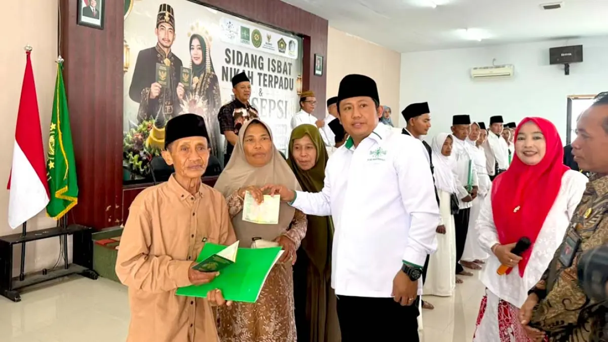 Bendahara Umum PCNU Banyuwangi H Junaedi menyerahkan buku nikah kepada pasangan suami istri usai menjalani Isbat Nikah di kantor PCNU Banyuwangi, Jumat (14/8). (Izul for Radar Banyuwangi)