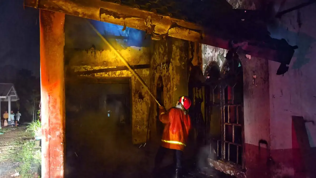 Petugas Damkarmat Sektor Genteng berjuang memadamkan api yang membakar rumah Paini, 54, di Dusun Pandan, RT 001/RW 004, Desa Kembiritan, Kecamatan Genteng, Banyuwangi, Jumat malam (14/8). (Salis Ali/Radar Banyuwangi)