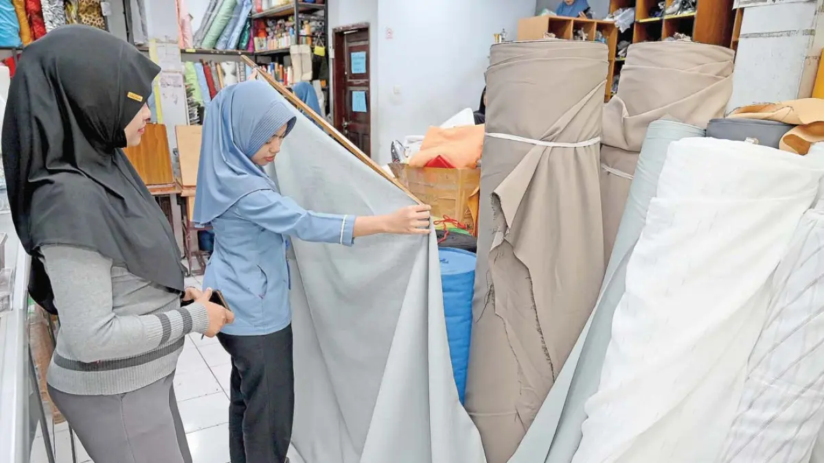SESUAI KEBUTUHAN: Konsumen memilih kain gorden di Laris Textile Banyuwangi. (Ramada Kusuma/Radar Banyuwangi)