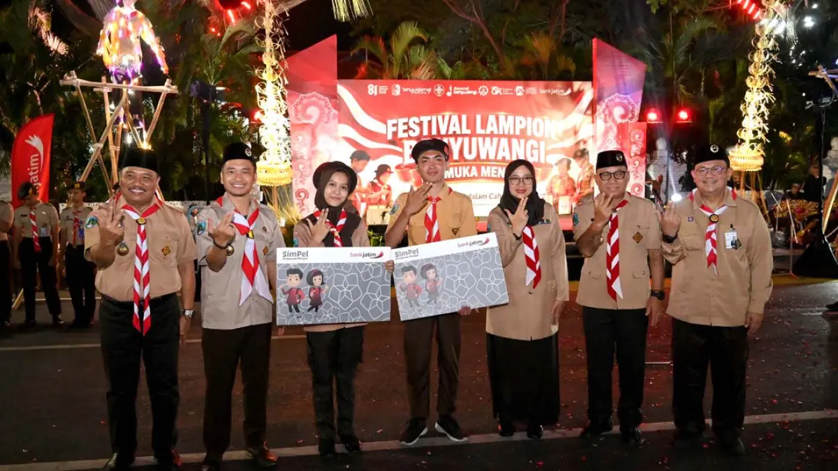 Bupati Ipuk Fiestiandani yang juga Kamabicab Banyuwangi didampingi Ketua Kwarcab Pramuka Mujiono, Plt Kadispendik Alfian, dan perwakilan Bank Jatim  Glemboh Priambodo menyerahkan program Satu Rekening Satu Pelajar (KEJAR) kepada perwakilan anggota Pramuka peserta Pawai Lampion pada Kamis malam (13/8). (Ramada Kusuma/Radar Banyuwangi)
