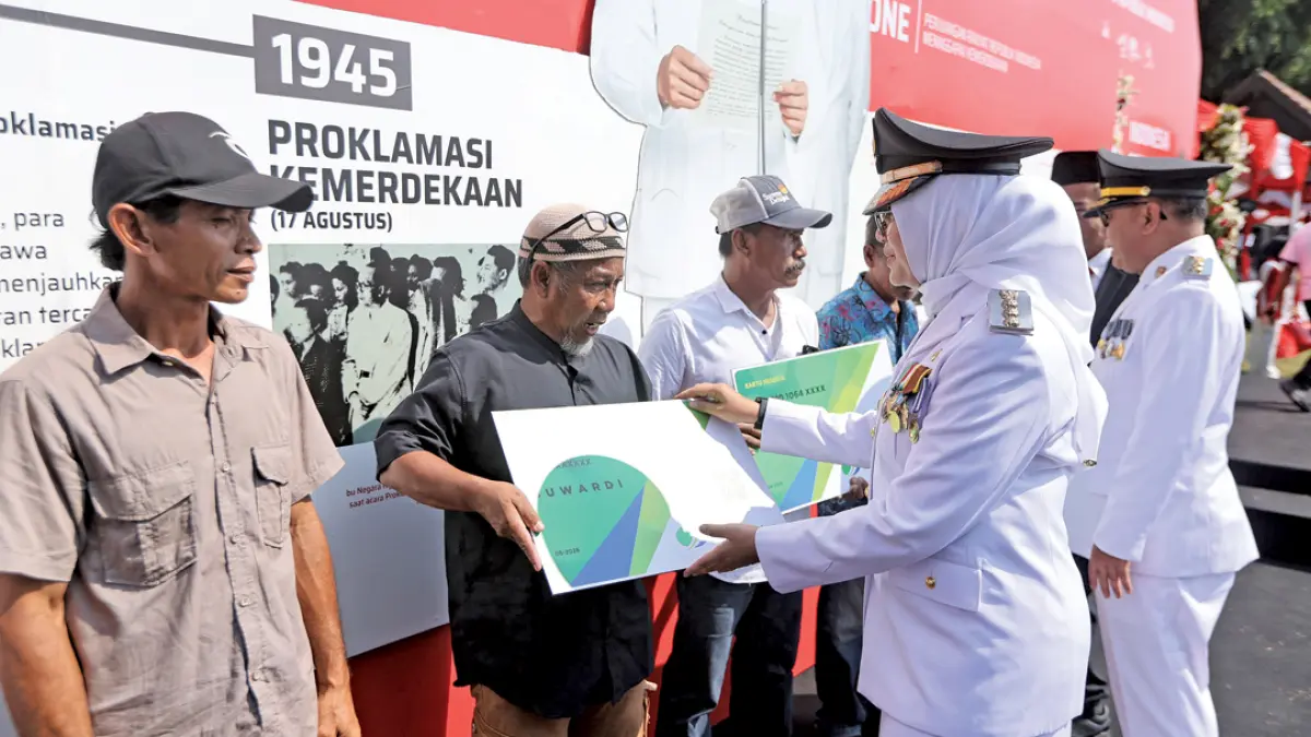 SIMBOLIS: Bupati Ipuk Fiestiandani bersama Wabup Mujiono menyerahkan bantuan pendaftaran perlindungan BPJS Ketenagakerjaan bagi pekerja informal di Taman Blambangan pada Selasa (17/8). (Humas Pemkab Banyuwangi)