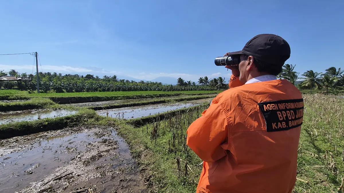 PAKAI TEROPONG: Petugas BPBD Jatim di Banyuwangi melakukan pemantauan titik kepulan asap di puncak Gunung Raung, Rabu (19/8). (Salis Ali/Radar Banyuwangi)