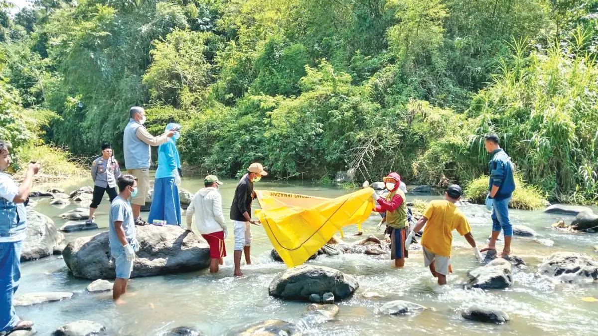 Petugas kepolisian bersama tim medis mengevakuasi jenazah yang ditemukan di aliran Sungai Dusun Ancar, Desa Gombolirang Kecamatan Kabat, Minggu (23/8). (Polsek Kabat untuk Radar Banyuwangi)