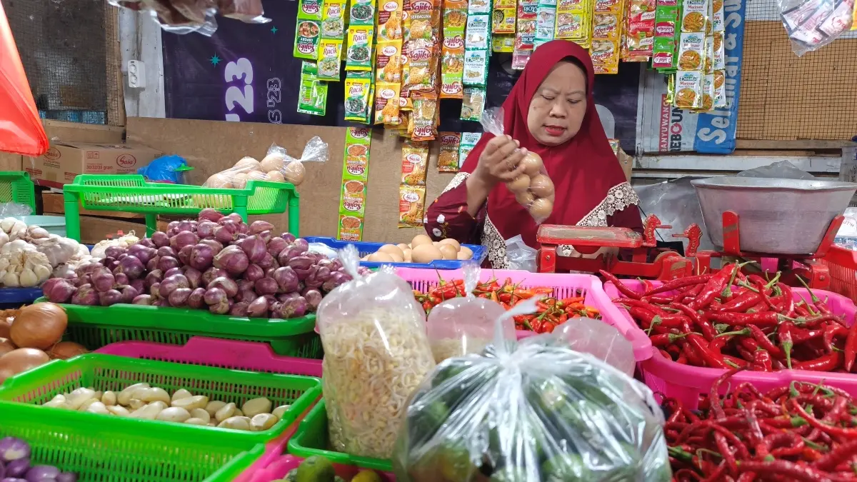 Salah satu pedagang sembako di Pasar Banyuwangi melayani pembelian telur pada Selasa (25/8). (Ksatria Raya/Radar Banyuwangi)