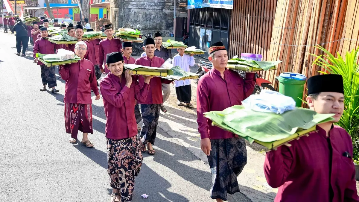 Warga Desa Kemiren membawa ancak dan endog-endogan menuju Masjid Nurul Huda dalam rangkaian peringatan Maulid Nabi Muhammad SAW 1448 Hijriah. (Ramada Kusuma/Radar Banyuwangi)