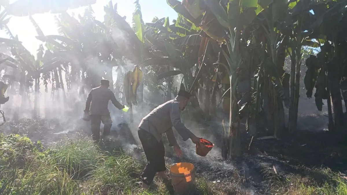 Petugas kepolisian memadamkan api yang membakar lahan semak kosong di tepi Pantai Muncar, Desa Kedungringin, Kecamatan Muncar, Jumat (4/9). (Kusmin for Radar Banyuwangi)