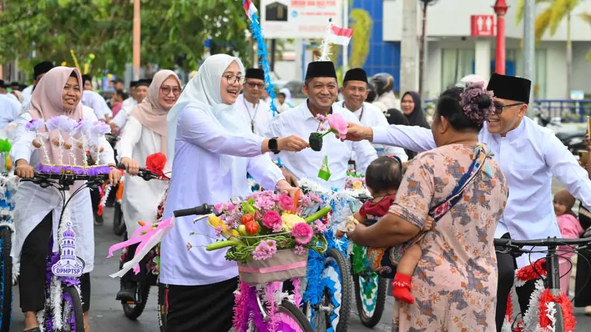 Seorang ibu sembari menggendong anaknya minta telur Maulid kepada Bupati Ipuk Fiestiandani disaksikan Abdullah Azwar Anas dan Kepala Dinas dalam pawai Endog-Endogan, kemarin (10/9). Pawai Endog-Endogan diberangkatkan dari depan Pendapa Sabha Swagata Blambangan. (Ramada Kusuma/Radar Banyuwangi)