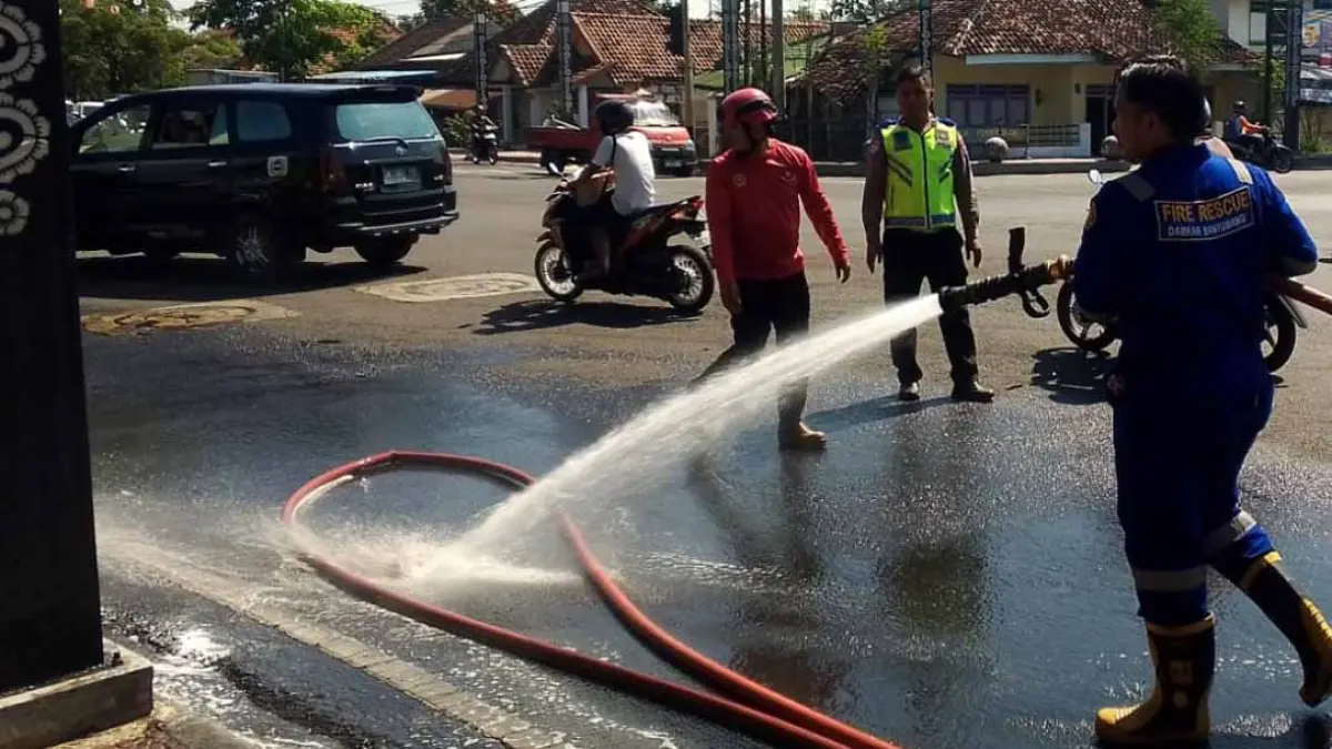 Petugas Damkarmat membersihkan tumpahan BBM di sebelah utara simpang empat Patung Kuda Jalan Adisucipto Banyuwangi, Sabtu (12/9). (Damkarmat Banyuwangi)