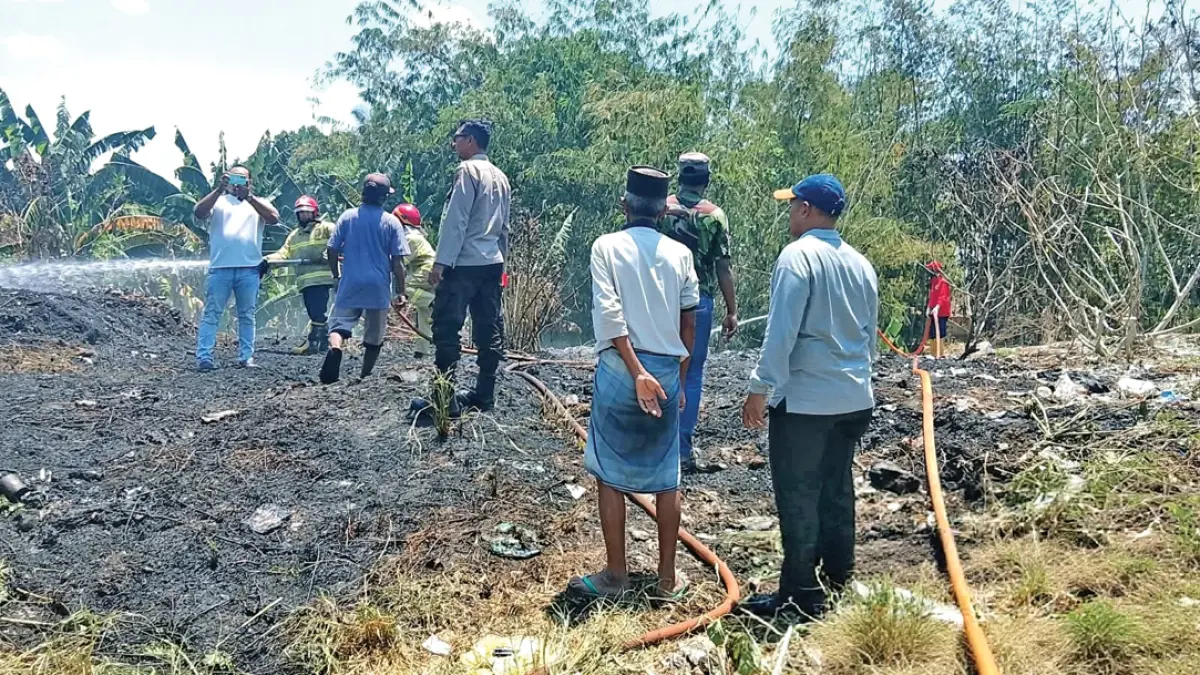 HANGUS: Petugas memadamkan api di lahan kosong di kawasan Pasar Hewan Rogojampi, Rabu (16/9). (Eko Baihaqi for Radar Banyuwangi)