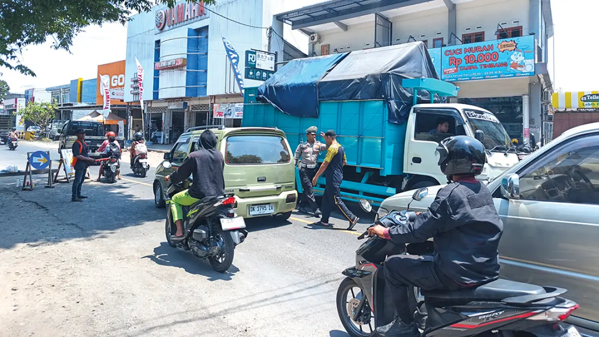 HARI TERAKHIR: Anggota Unit Lantas Polsek Rogojampi mengatur lalu lintas di kawasan jembatan yang diperbaiki di Jalan Raya Kecamatan Rogojampi, Jumat (18/9). (Zamrozi Wahyu/Radar Banyuwangi)